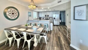 Una cocina moderna con una isla central, muebles blancos y una lámpara de araña.
