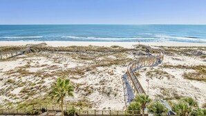 A beach with a wooden boardwalk leading to the water, surrounded by sand dunes and sparse vegetation. - Gulf Front Beach Club - Renovated Corner Condo, Direct Gulf Views! Pool, WIFI (Gulf Shores)