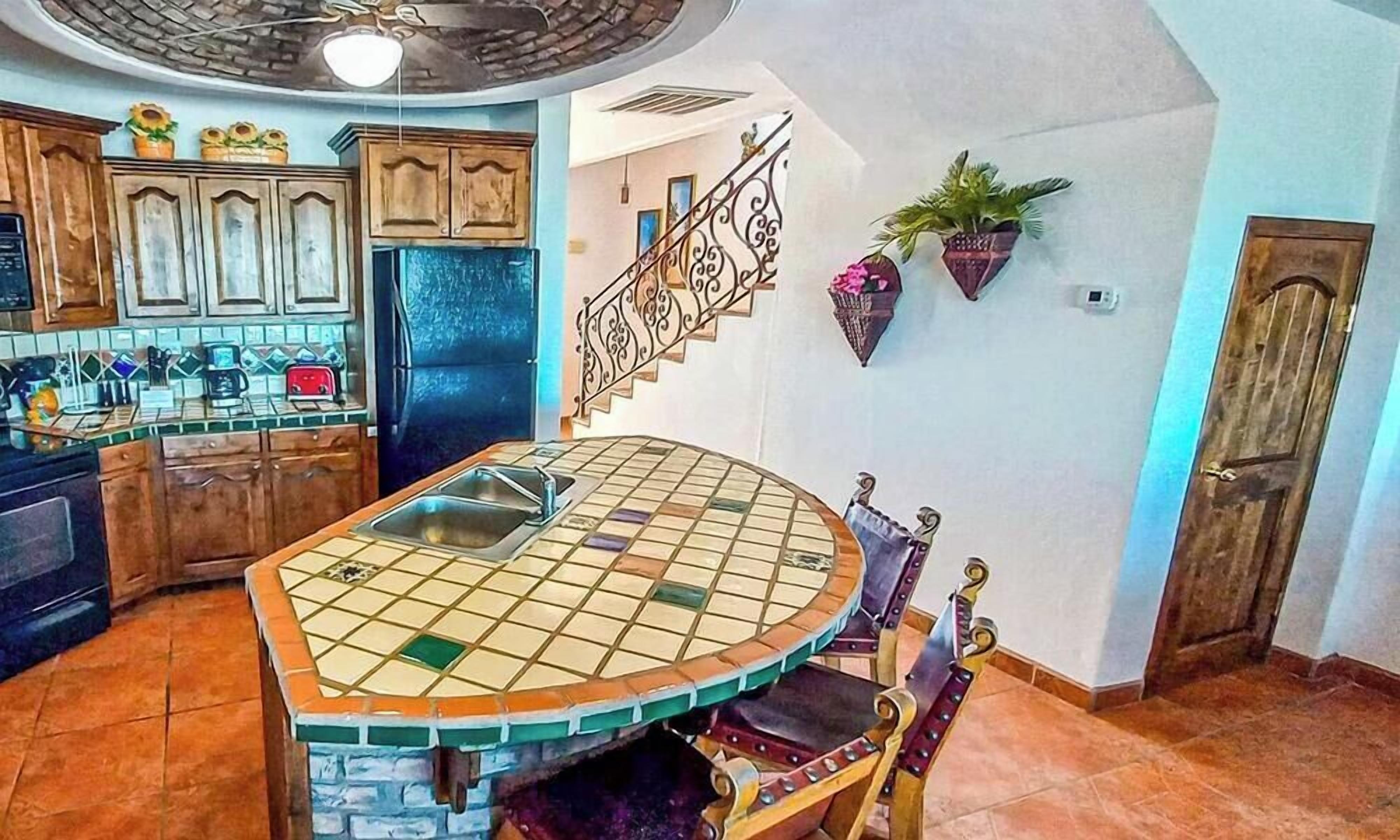A kitchen with a tiled island, wooden cabinets, and a built-in refrigerator.