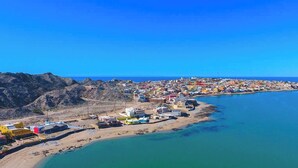 A coastal town with buildings along the shoreline, a clear blue sky, and a calm sea.