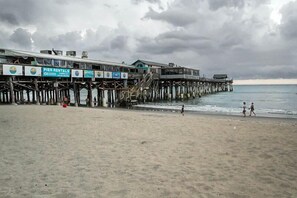 Een steiger met meerdere niveaus en een strand op de voorgrond.
