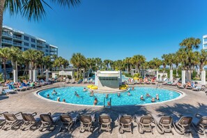 A pool area with multiple levels of balconies, palm trees, and lounge chairs.