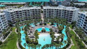 Un resort con varias piscinas, palmeras y vista al océano.