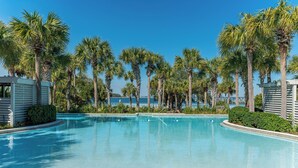 A swimming pool surrounded by palm trees and a view of the ocean.