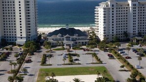 Un hôtel doté d’un bâtiment principal entouré d’un parking, d’une plage et offrant une vue sur l’océan.