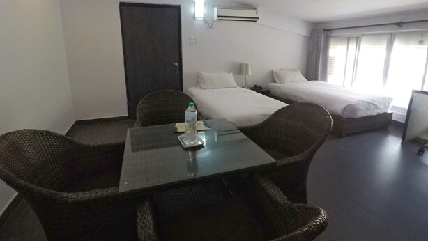 Une chambre d’hôtel équipée d’une table à manger, de deux lits, d’une bouteille d’eau et d’un appareil de climatisation.