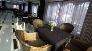 Un espace de restauration d'hôtel avec des chaises en osier, une table et un vase de fleurs.