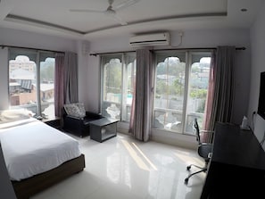 A hotel room with a bed, a desk, a chair, and large windows. - Bhutan Residence (Phuntsholing)