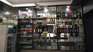 Un espace bar avec des étagères remplies de différentes bouteilles et de verres, un ventilateur de plafond et un écran de télévision.