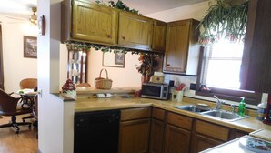Una cocina con gabinetes de madera, microondas, fregadero y lavavajillas.