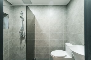A modern bathroom with a shower, toilet, and sink.