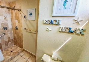 Ein Badezimmer mit Dusche, Toilette und einer Wand mit der Aufschrift 'BEACH RELAX' sowie Meeresstern-Dekorationen.