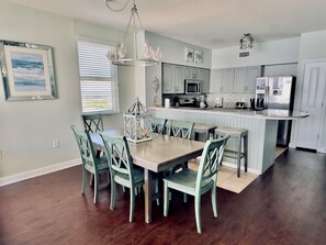 A modern kitchen with a dining area, featuring a central island, wooden cabinets, and a chandelier.