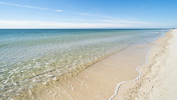 Una spiaggia con acque limpide e una costa sabbiosa.