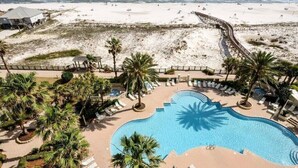 Un resort con una grande piscina, accesso alla spiaggia e palme.