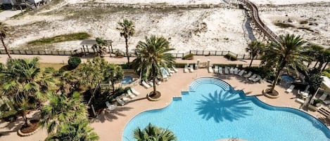 A resort with a large pool, beach access, and palm trees.