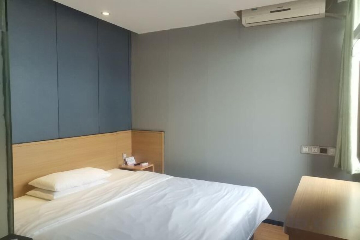 A hotel room with a bed, bedside table, and a chair.
