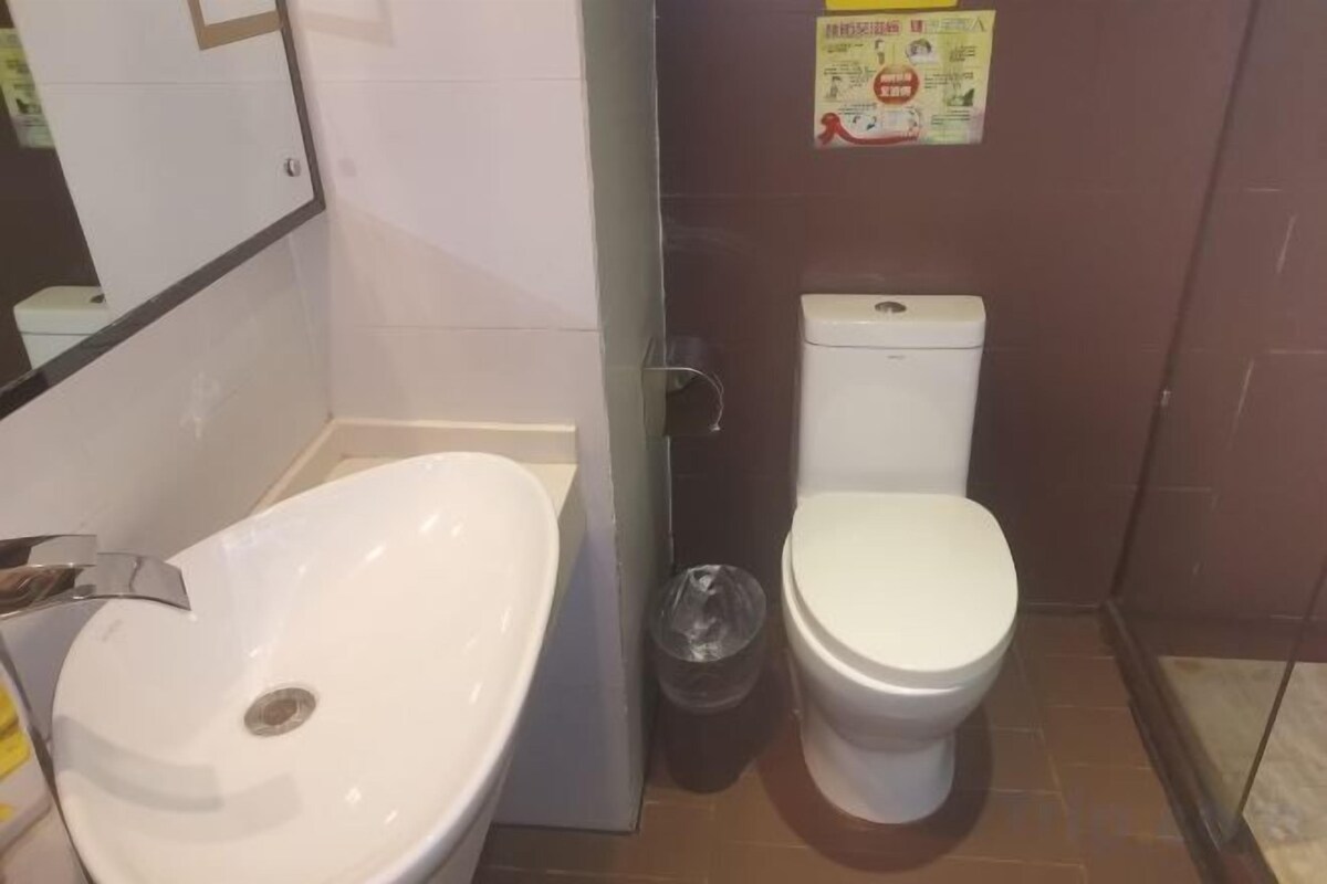A bathroom with a white sink, toilet, and a glass shower enclosure.
