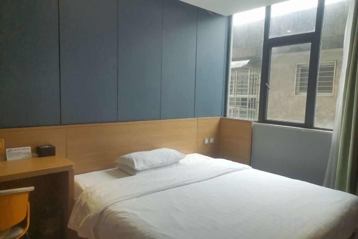 A hotel room with a bed, a desk, and a window.