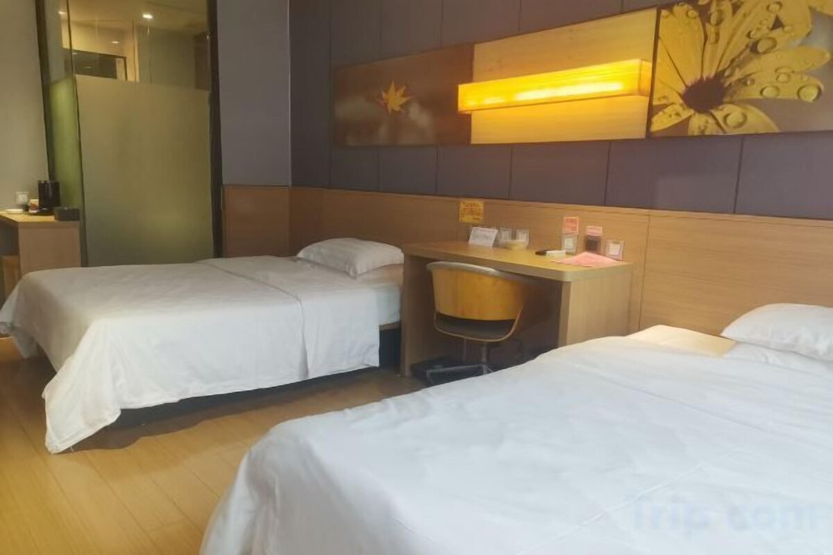 A hotel room with two beds, a desk, and a chair.