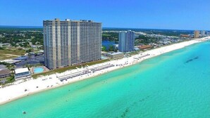 Een hoog hotel met uitzicht op het strand, nabij een kustlijn met helder turquoise water.