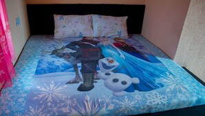 Una cama con un edredón de tema Frozen, almohadas con personajes de dibujos animados y una cortina rosa.