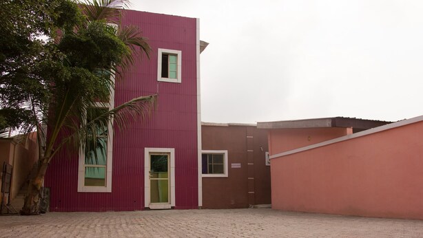 Un edificio con fachada roja, puerta verde y una ventana pequeña.