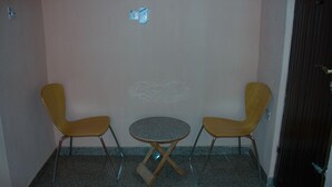 Una habitación pequeña con dos sillas amarillas y una mesa redonda.