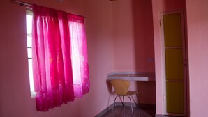 Una habitación con pared rosa, un escritorio de madera, una silla amarilla y una puerta con panel amarillo.