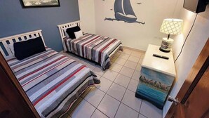 A bedroom with two beds, a nightstand with a lamp, and a wall mural. - Family Condo Sea View Pool | 3bdr Sleeps 7 (Penasco)