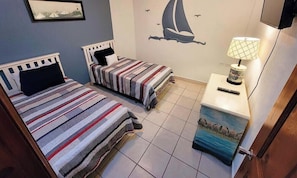 Un dormitorio con dos camas, una mesita de noche con lámpara y un mural en la pared.