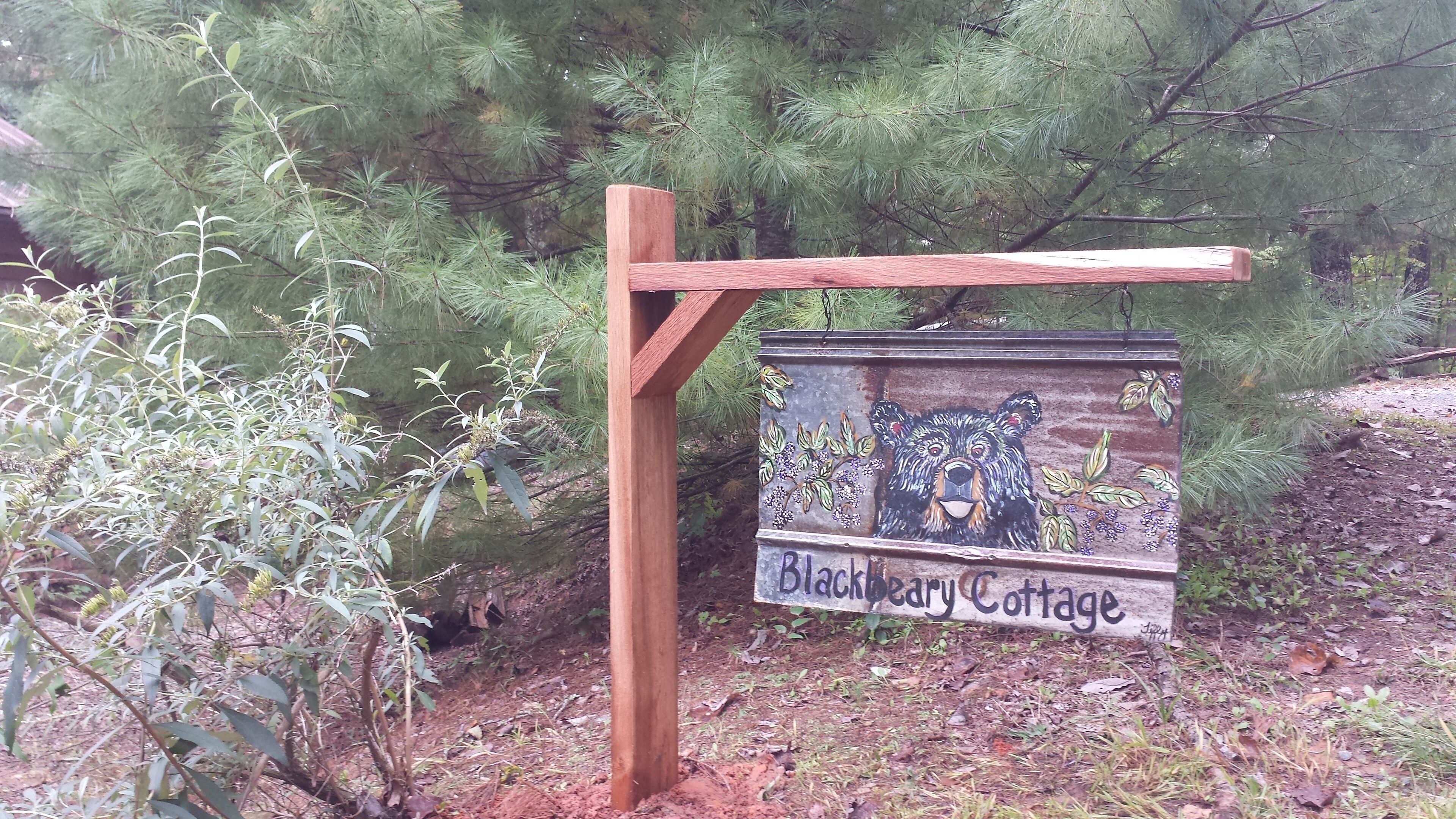 A wooden sign with a bear illustration and the text "Blackberry Cottage".