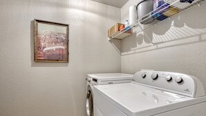 A laundry room with a washing machine, dryer, and a shelf with cleaning supplies. - Family Friendly Charming +Clean 5 Bedroom House, (Monument)