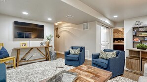 A living room with two blue armchairs, a wooden coffee table, and a TV mounted on the wall. - Family Friendly Charming +Clean 5 Bedroom House, (Monument)