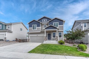A two-story residential building with a front porch, a garage, and a well-maintained lawn.