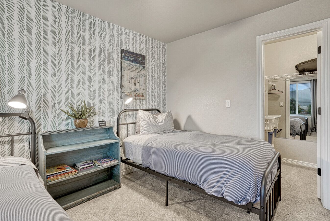 Un dormitorio compacto con una cama individual, un escritorio pequeño con una planta y un espejo en la pared.