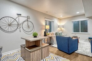 A modern living room with a wooden coffee table, a blue sofa, and a wall-mounted bicycle.