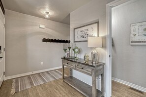 Un couloir avec une console en bois, un porte-manteau mural et une pancarte de bienvenue.