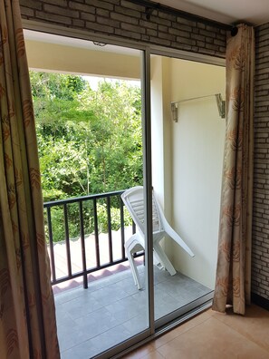 A balcony with a glass door, a white plastic chair, and a metal railing.