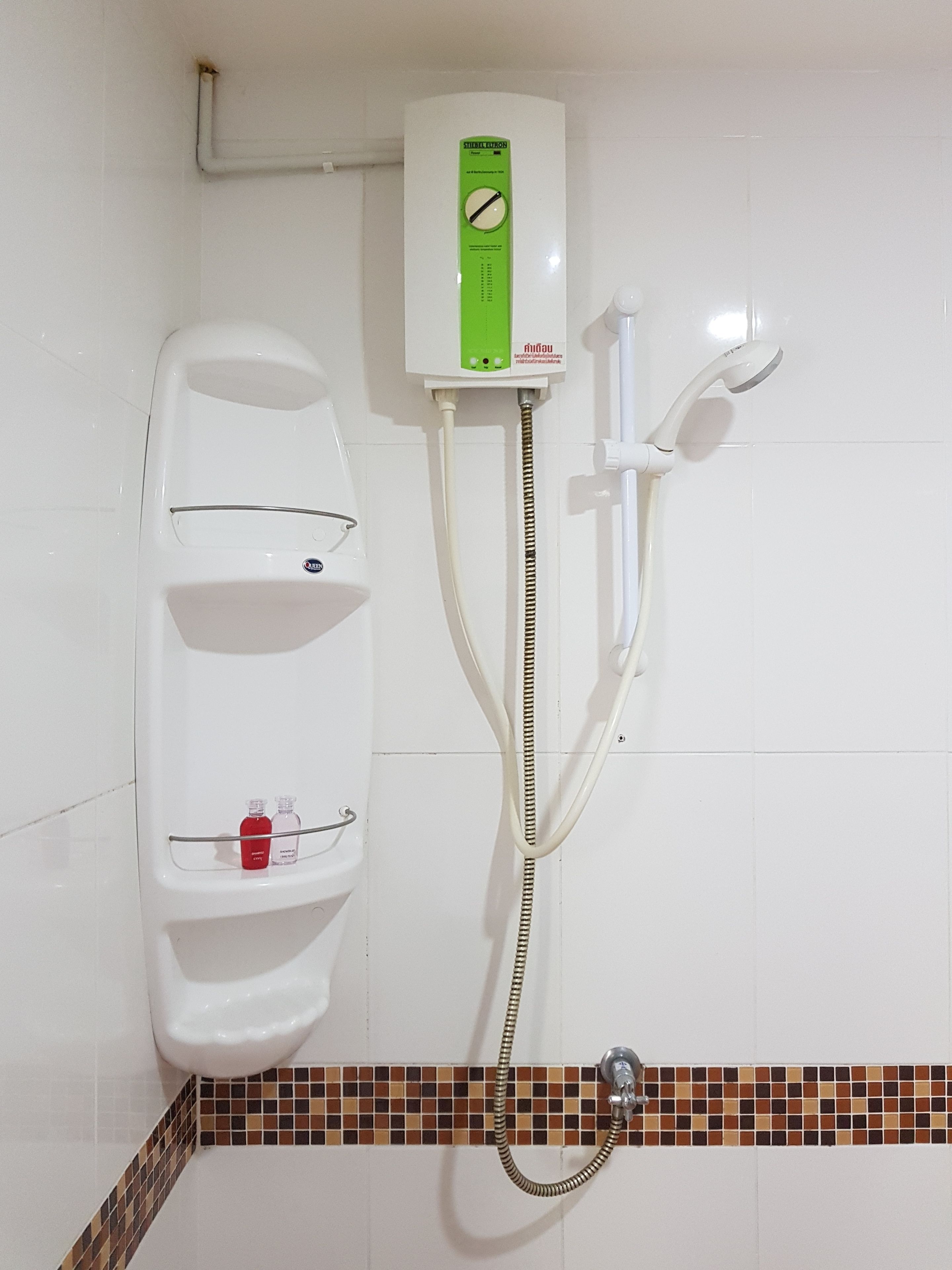 A shower enclosure with a control panel, a handheld showerhead, and a wall-mounted faucet.