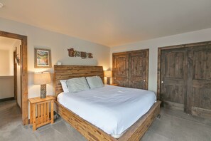 Cozy retreat with a large bed, wooden headboard, and a nightstand with a lamp.