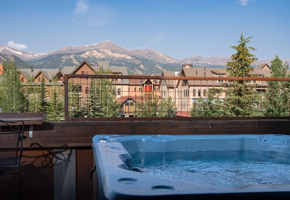 Relax in a tranquil hot tub with a breathtaking mountain view from a deck with a seating area.