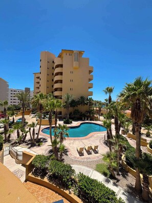 Ein Hotel mit Swimmingpool, Palmen und blauem Himmel.