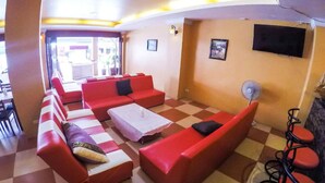 A hotel lobby with red sofas, a checkered floor, a white table, and a fan. - Sunshine Coast Inn (Pattaya)
