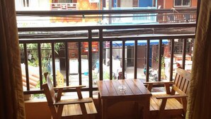A balcony with wooden furniture, a tiled floor, and a view of buildings in the background. - Sunshine Coast Inn (Pattaya)
