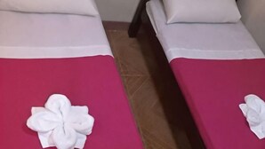 Deux lits avec des oreillers blancs et des couvre-lits rouges, chacun étant agrémenté d’une serviette blanche posée sur le lit.