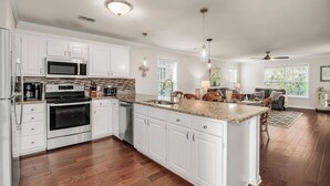 A modern kitchen with white cabinets, stainless steel appliances, and a large island.