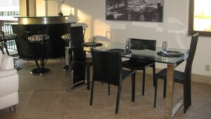 Un comedor con una mesa de vidrio, sillas negras y una barra negra.