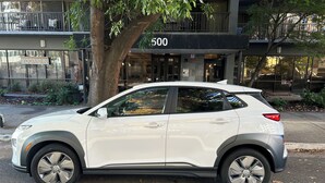 Un SUV blanco estacionado en una calle, con un edificio que muestra el número '500' al fondo.