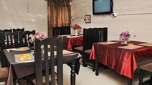 A dining area with multiple tables covered with red tablecloths, wooden chairs, and floral centerpieces. - Golden King Apartment Hotel (Lagos)